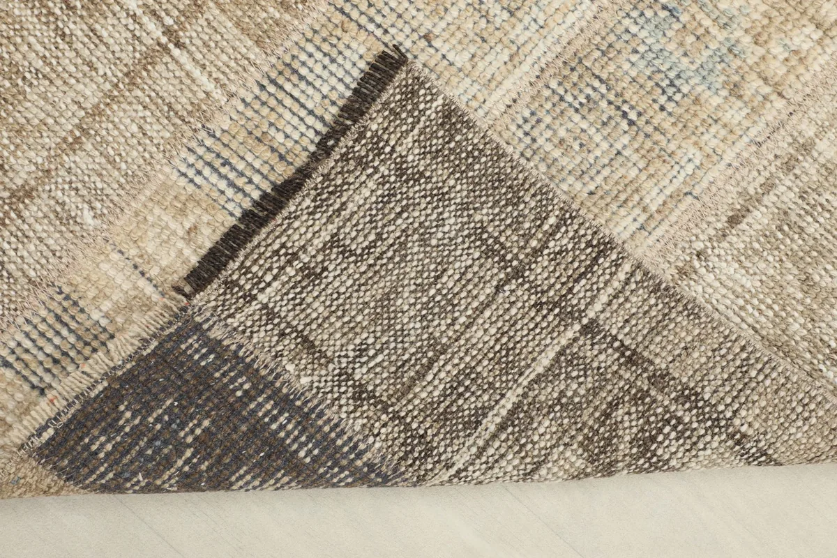 Corner of the rug folded back to reveal the cotton foundation and the reverse side of the hand-knotting.