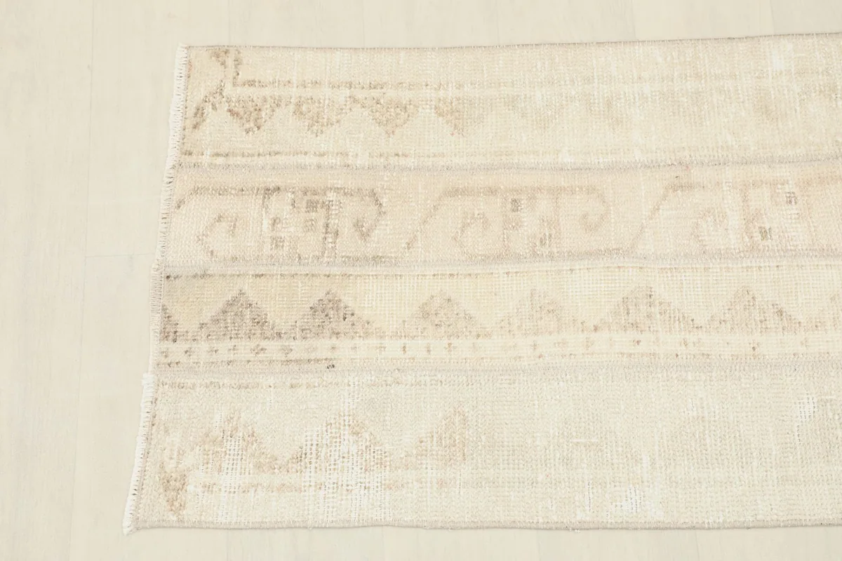 Detailed view of the rug's patterns and texture, focusing on the natural wear and variations in color.
