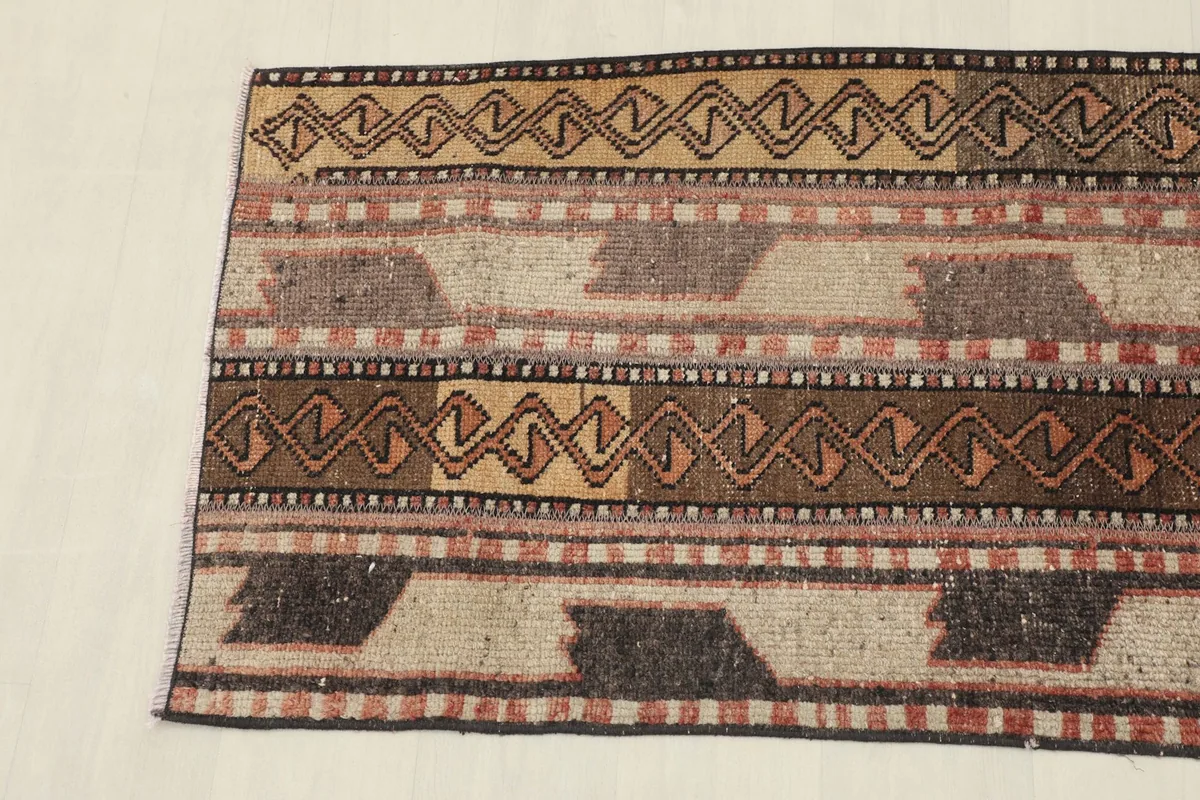 Detailed view of the rug's surface, showing the interwoven brown, tan, and rust motifs.