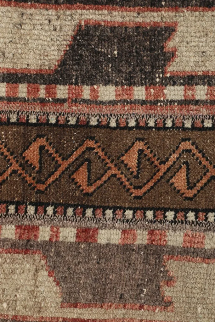 Macro detail of the hand-knotted construction and the specific zig-zag and block patterns.