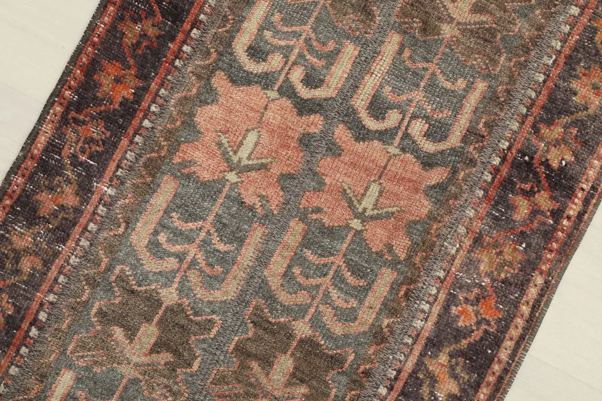 Close-up of the rose and gray geometric patterns, revealing the hand-knotted wool pile.