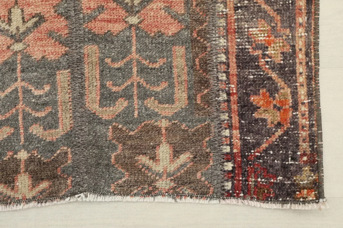 Detail of one end of the rug, showing the faded colors and short cotton fringes.