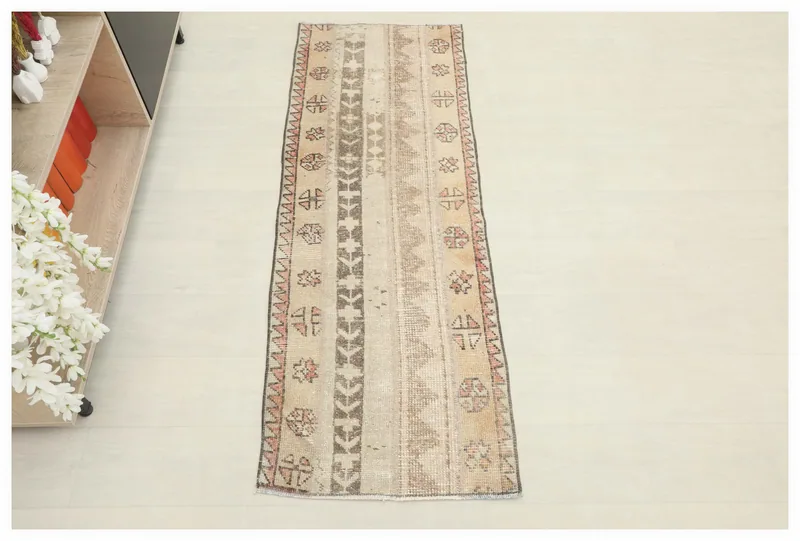 Full overhead view of the beige and brown vintage Anatolian runner rug on a white background.