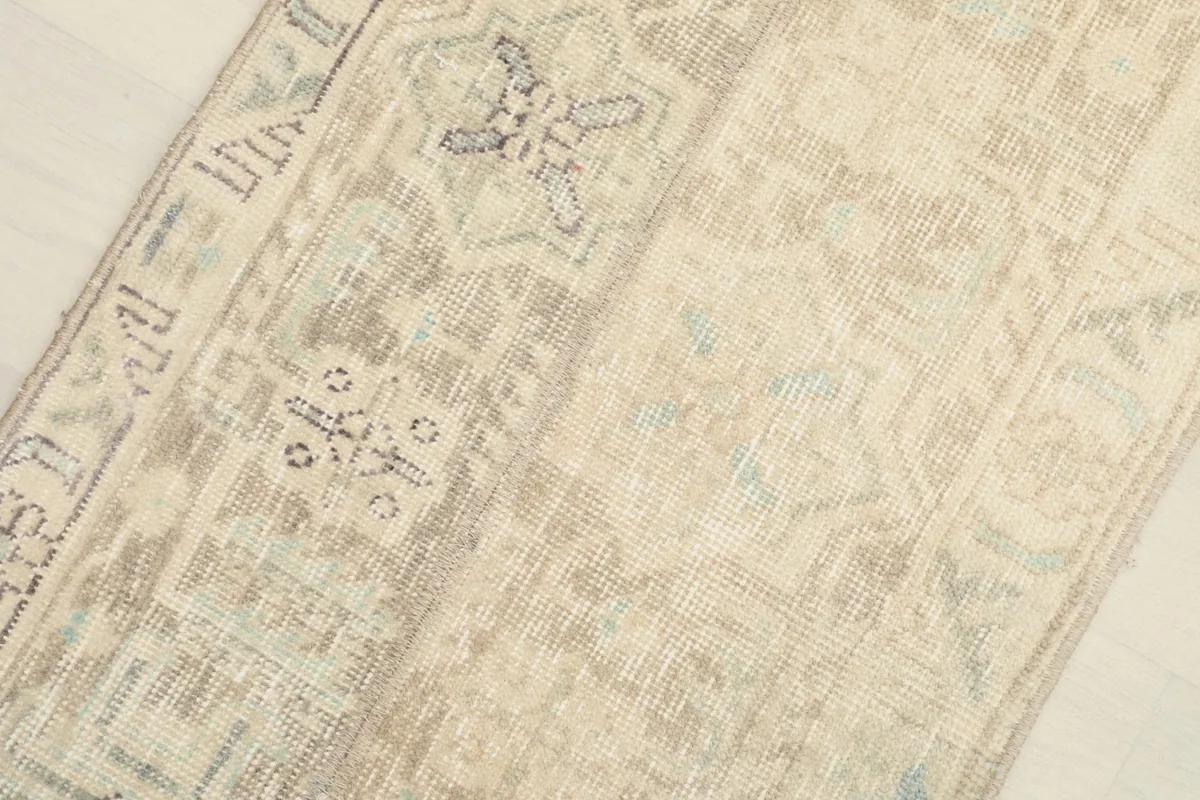 Close-up on a specific section of the rug, illustrating the hand-knotted craftsmanship and faded patterns.