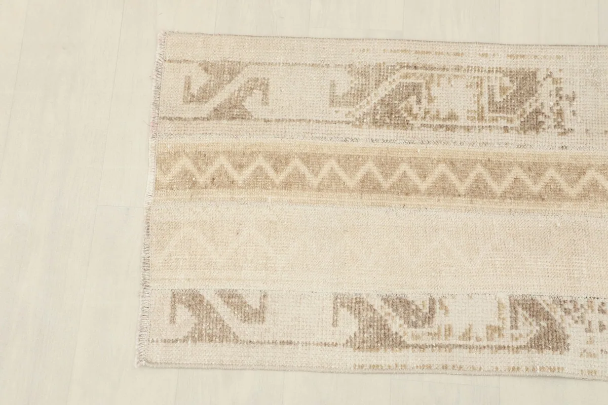 Detailed view of the rug's tribal motifs and chevron pattern in beige and tan.