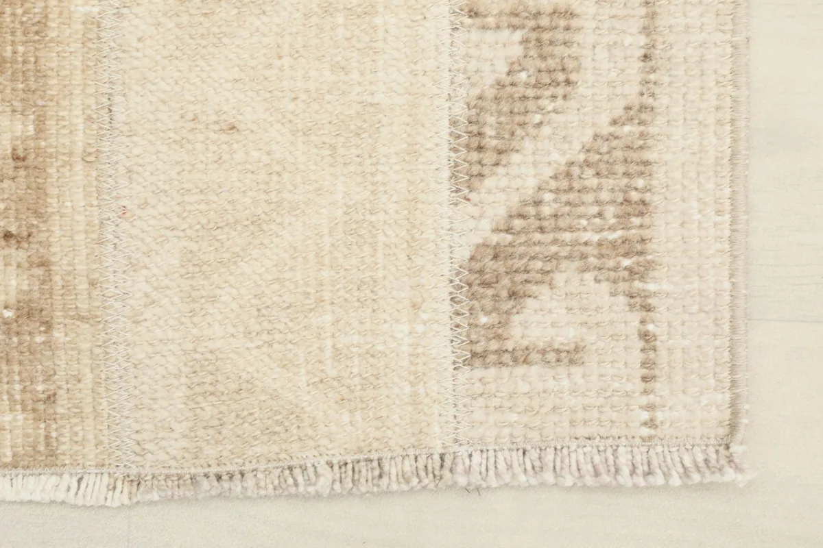 Close-up of the rug's edge, showing the short, natural cotton fringe and tight knotting.