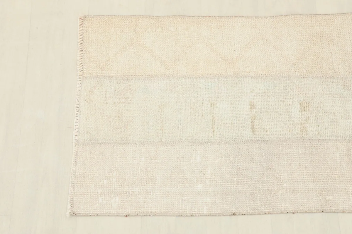 Detailed view of the rug's surface, showing faint geometric patterns within the cream and beige patches.