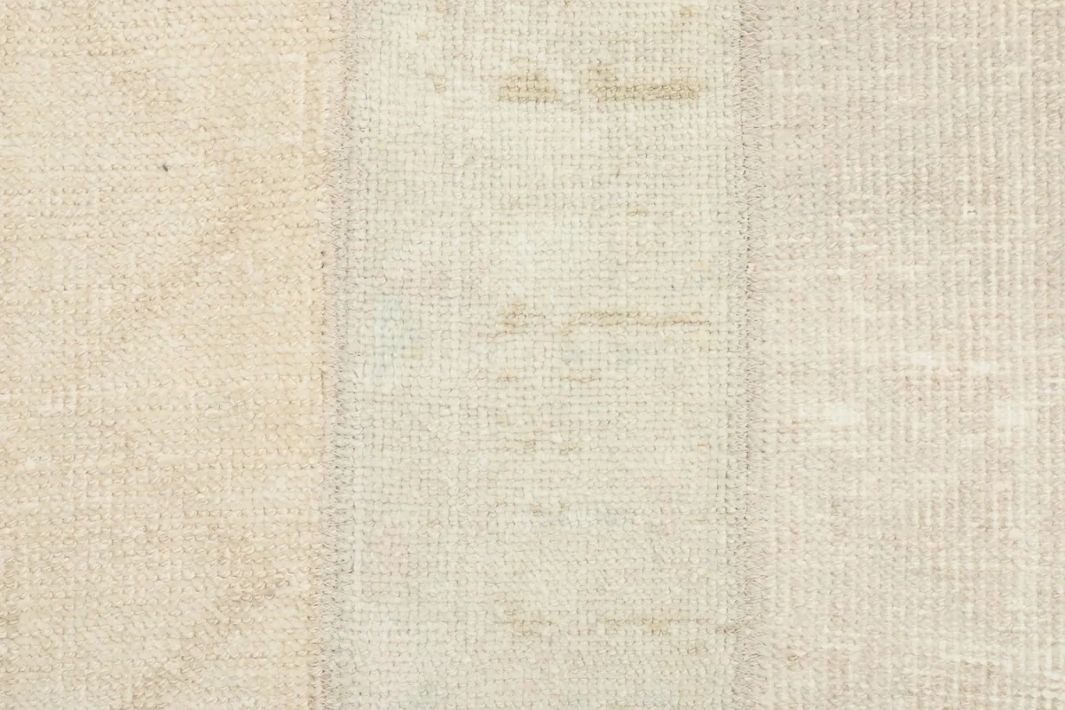 Close-up shot of the rug's low pile, showing the hand-knotted texture and natural variations in color.