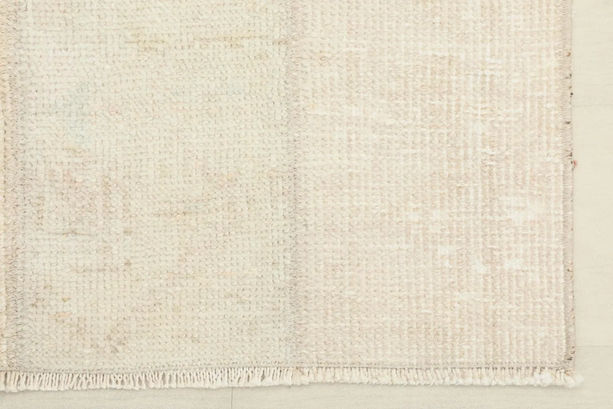 Detail of one end of the rug, showing the short, natural fringe and the hand-finished edge.
