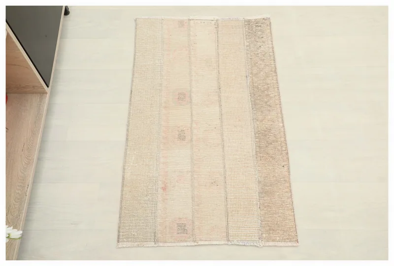 Full top view of the 1'11" x 3'2" cream and beige striped vintage Anatolian rug on a white floor.