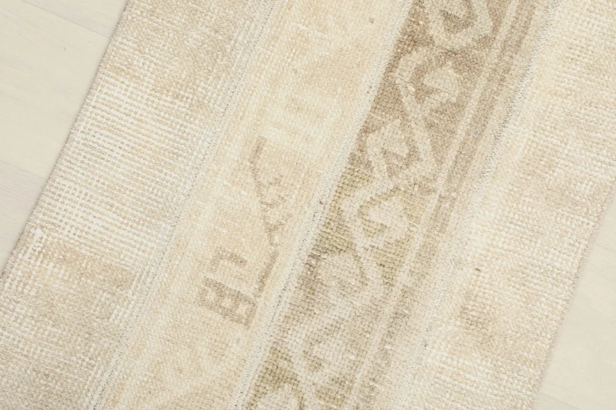 Close-up of the textured wool pile and the subtle color shifts within the beige and tan patterns.