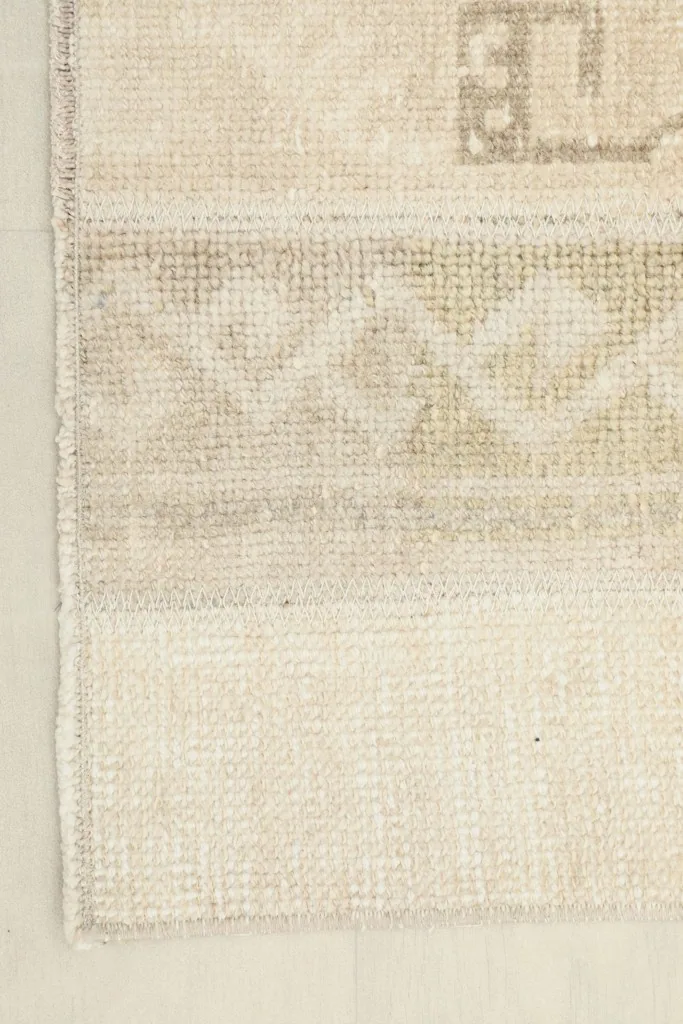 View of the edge and fringe of the beige area rug, showing the finishing details.