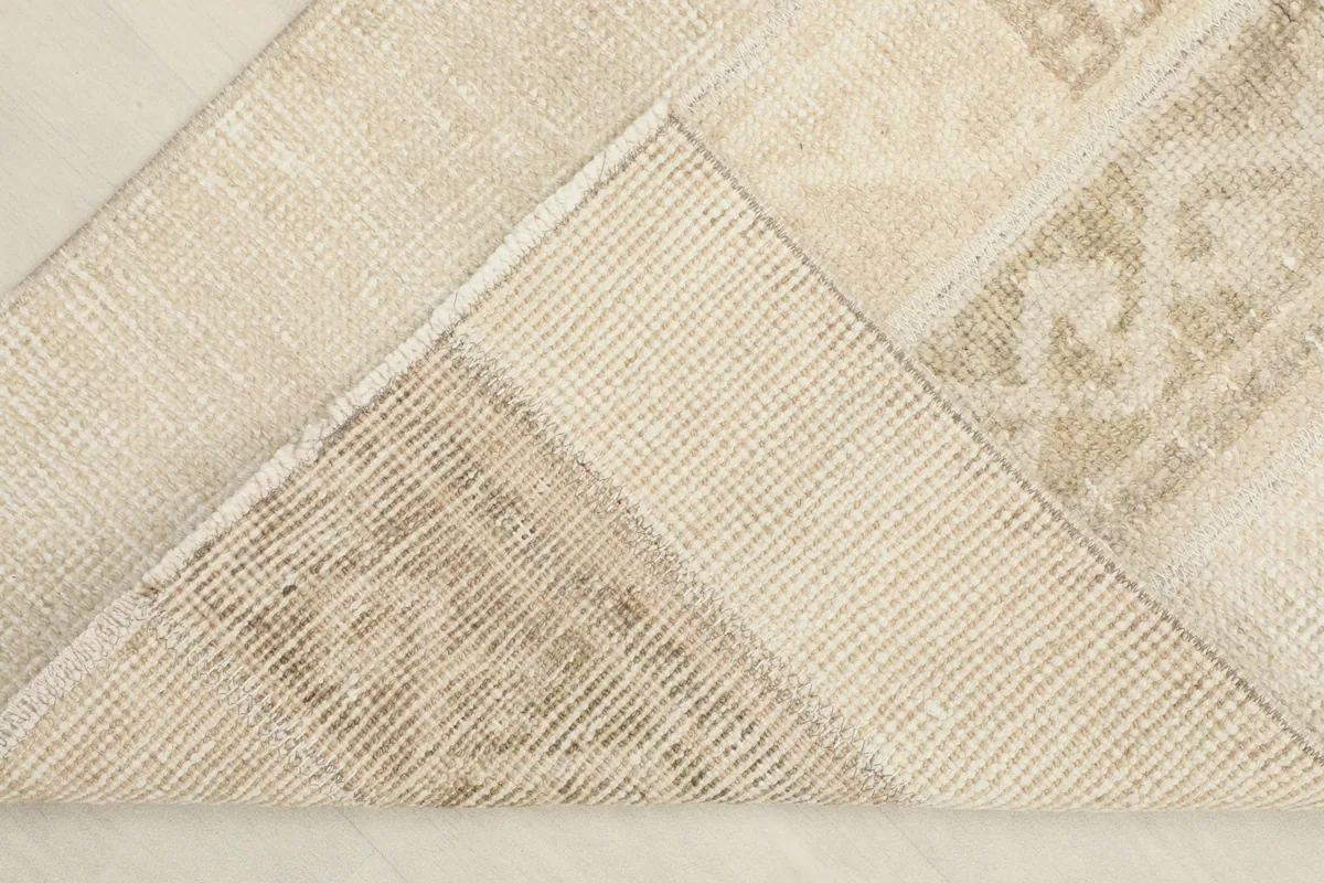 Underneath view of a corner of the rug, showing the cotton foundation and reverse side of the knots.