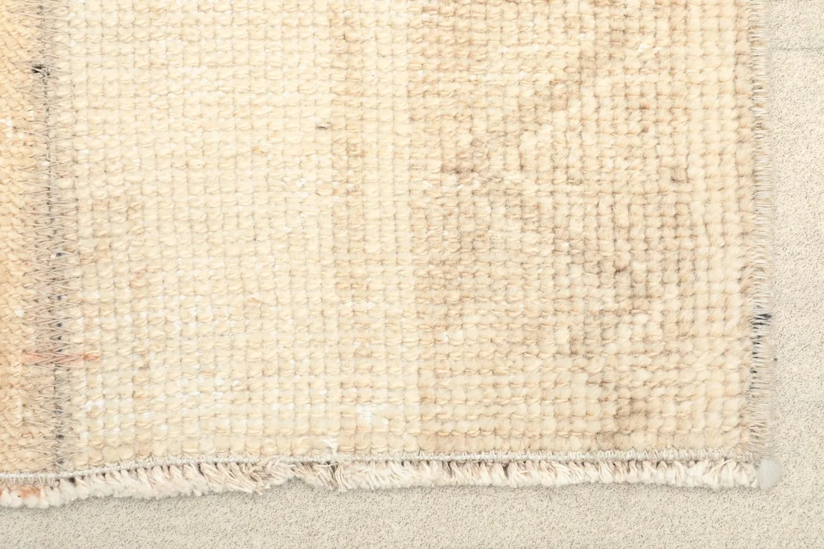 Close-up detail of one end of the rug, showing the low wool pile and short fringes.