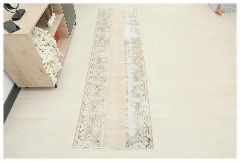 Full overhead view of the beige and blue vintage Anatolian runner rug on a light floor.