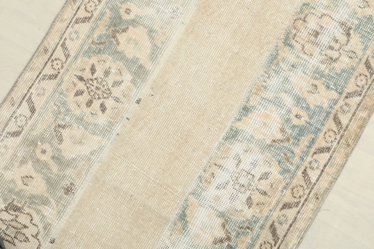 Close-up detail of the rug's central beige field and the adjacent patterned blue and cream sections.