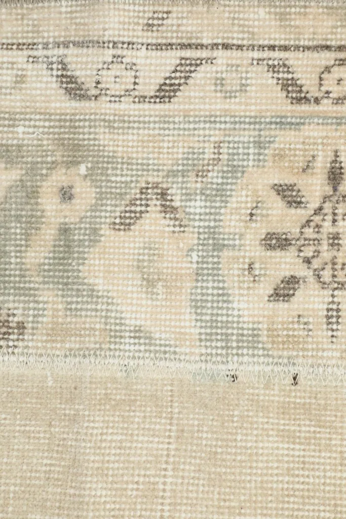 Detailed view of the faded blue and brown geometric motifs within the patterned border of the runner.