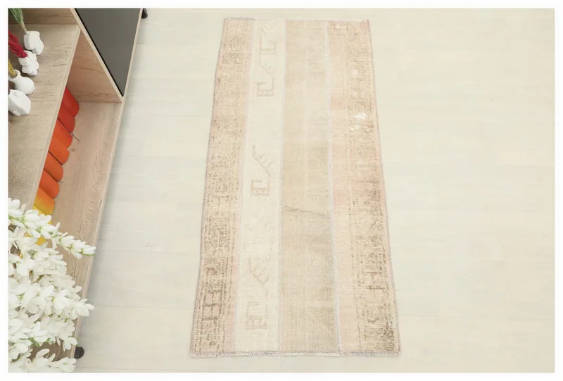 Full overhead view of the beige patchwork Anatolian runner on a white floor.