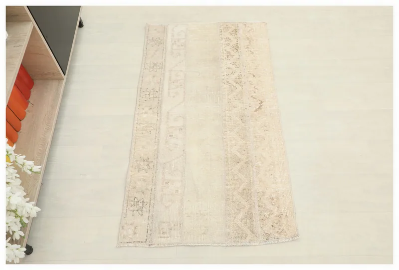 Full top view of the ivory and beige vintage Anatolian rug on a white floor.