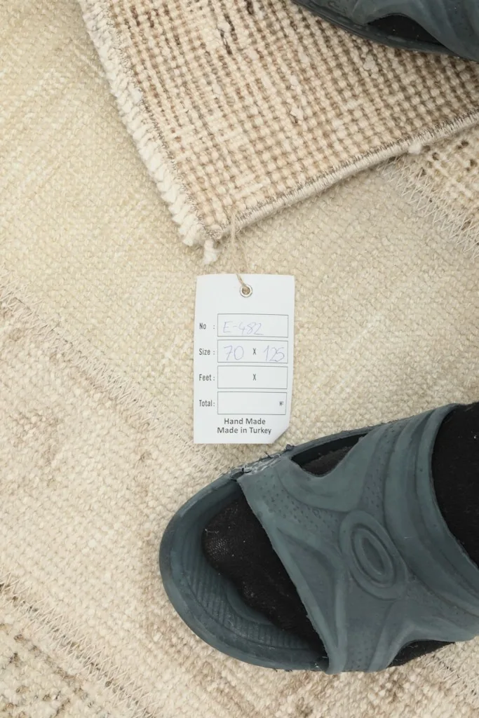 Close-up of the rug's texture next to a label showing size and origin, with a shoe for scale.