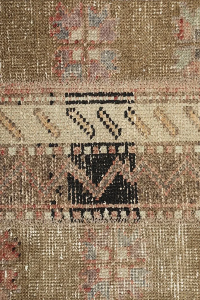Macro detail of a central black geometric motif within a beige panel.