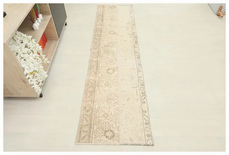 Full top view of the beige and gray floral vintage Anatolian runner rug on a white background.
