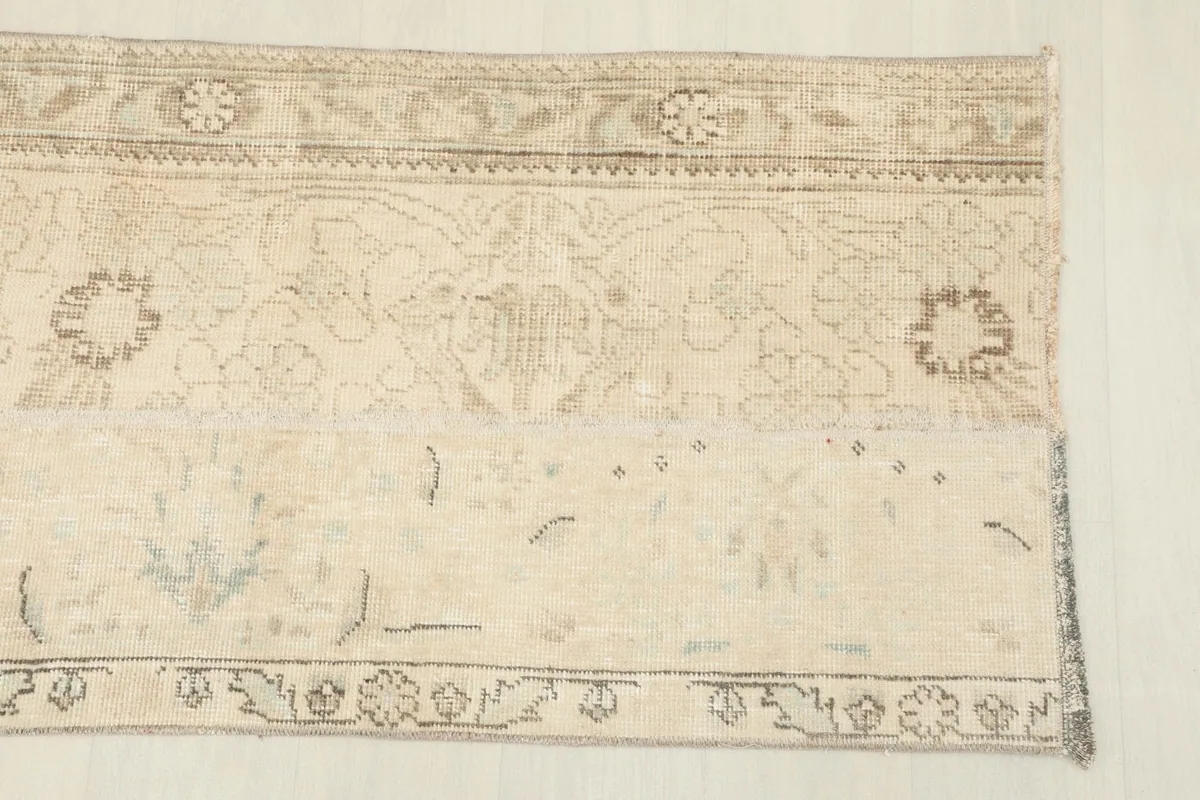 Close-up of the beige runner showing faded gray and tan floral and geometric motifs.
