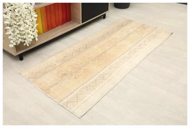 Full overhead view of the beige and tan vintage Anatolian rug on a white floor
