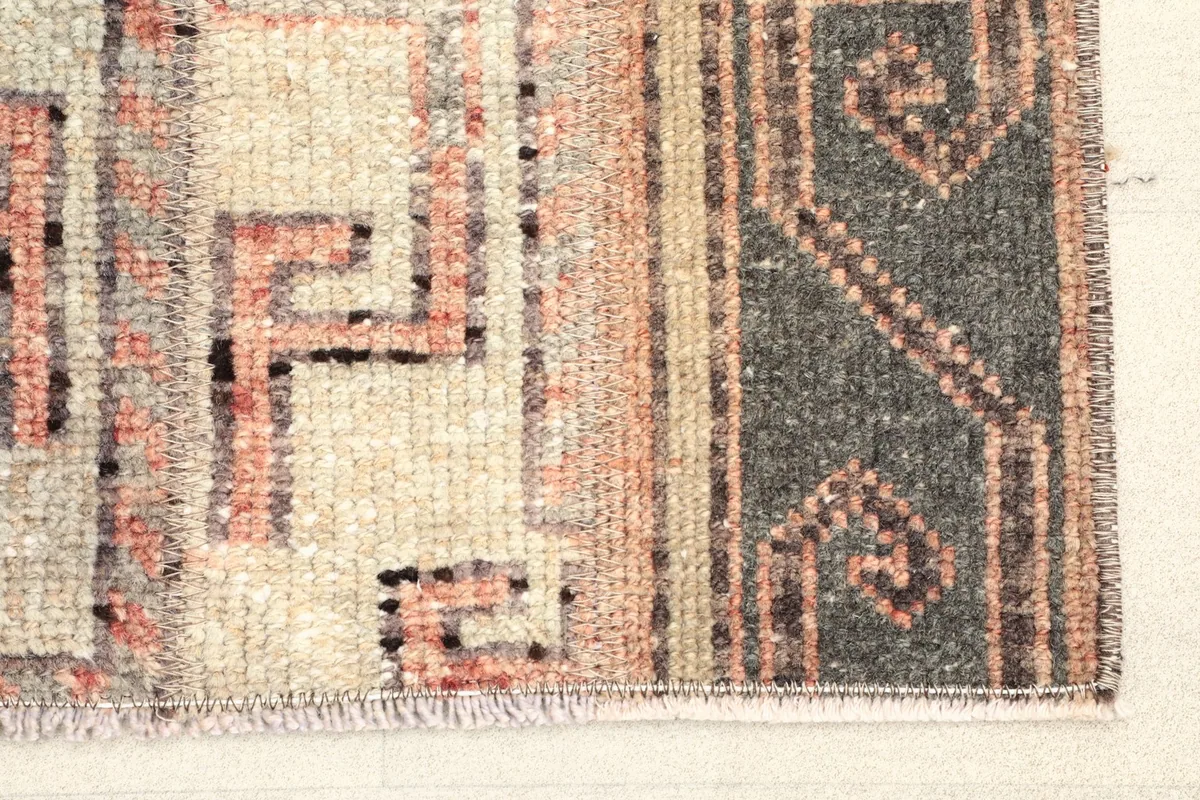 Close-up detail of the rug's corner, showing the rust and gray geometric motifs
