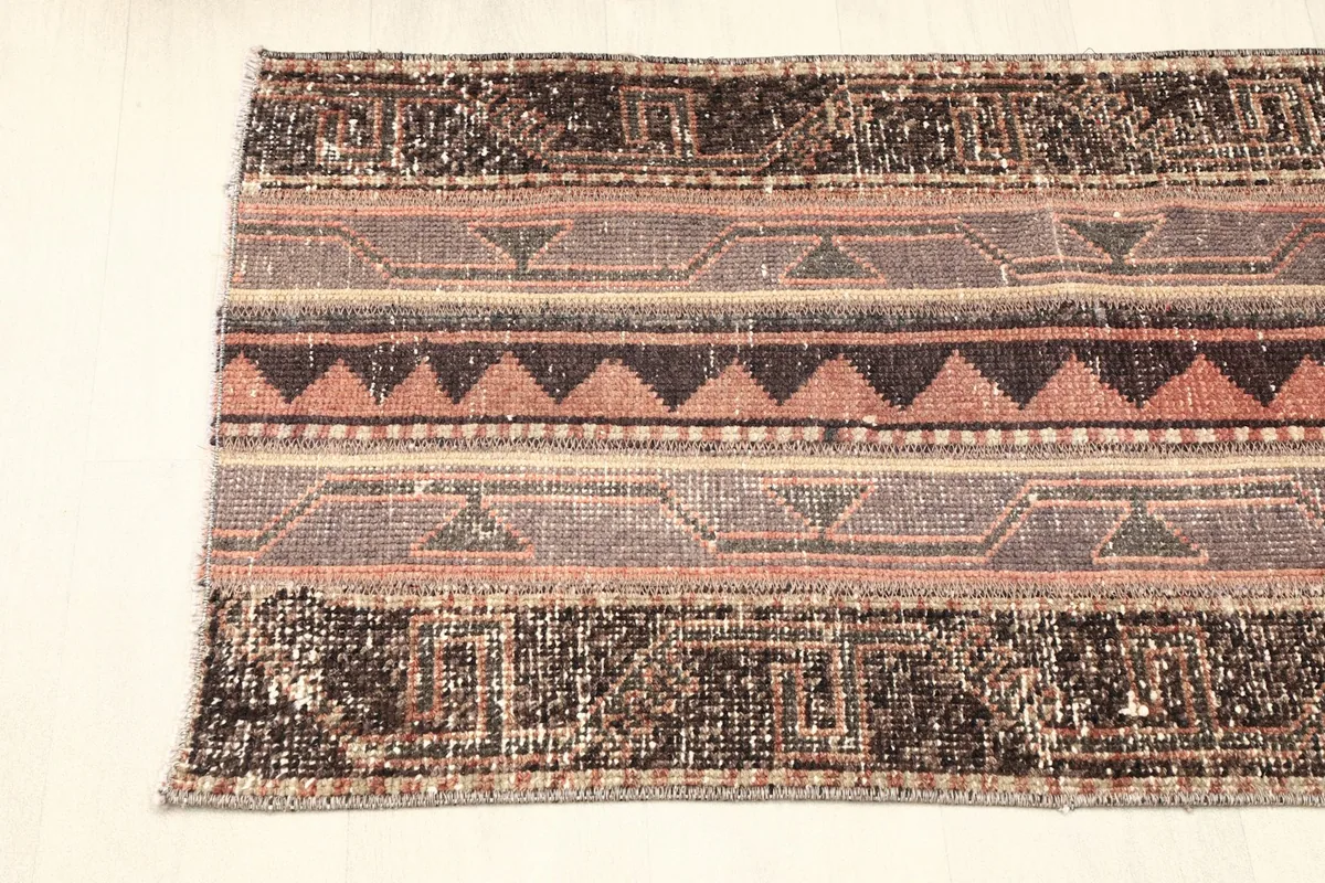 Partial view of the rug from one end, showing the striped design and colors.