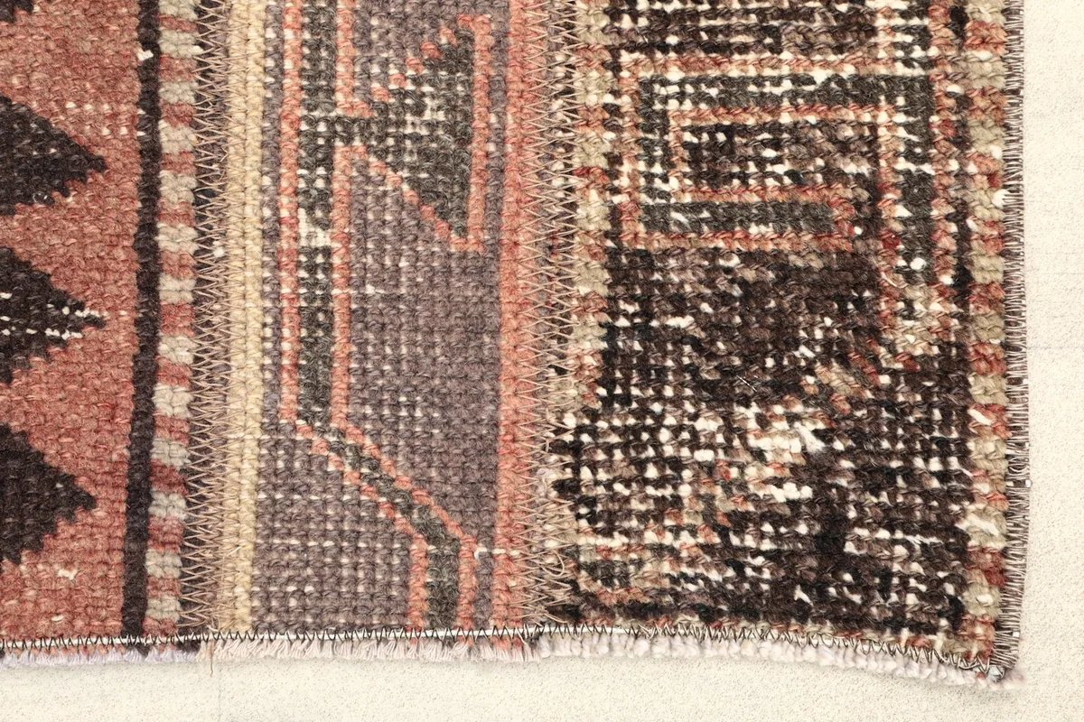 Close-up detail of the rug's edge, showing the hand-knotted texture and distinct brown and rust patterns.