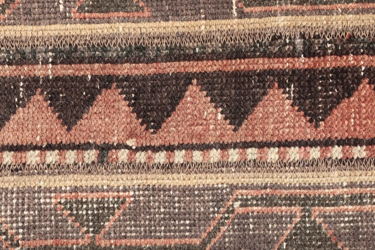 Macro detail of the central rust-colored geometric pattern with black and beige triangular shapes.