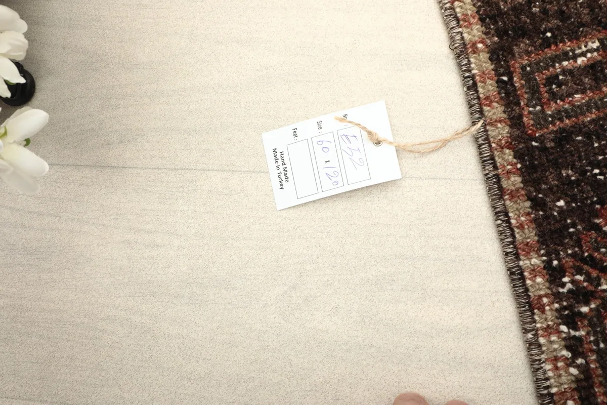A partial view of the rug on the floor with a product tag visible, showing scale.