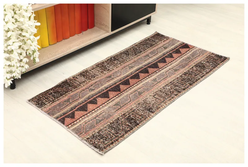 Full overhead view of the rust and brown tribal geometric rug on a white background.