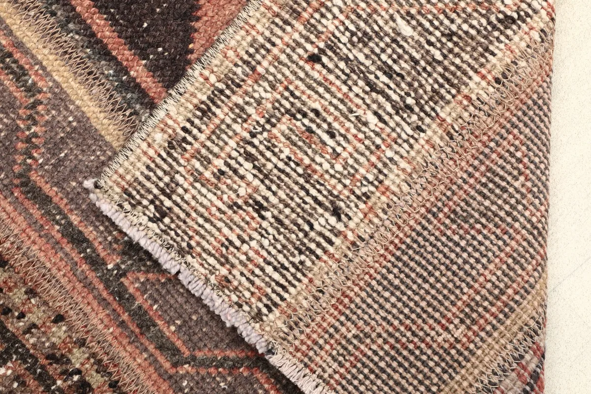 Close-up of the rug's folded corner, revealing the wool pile and cotton foundation.