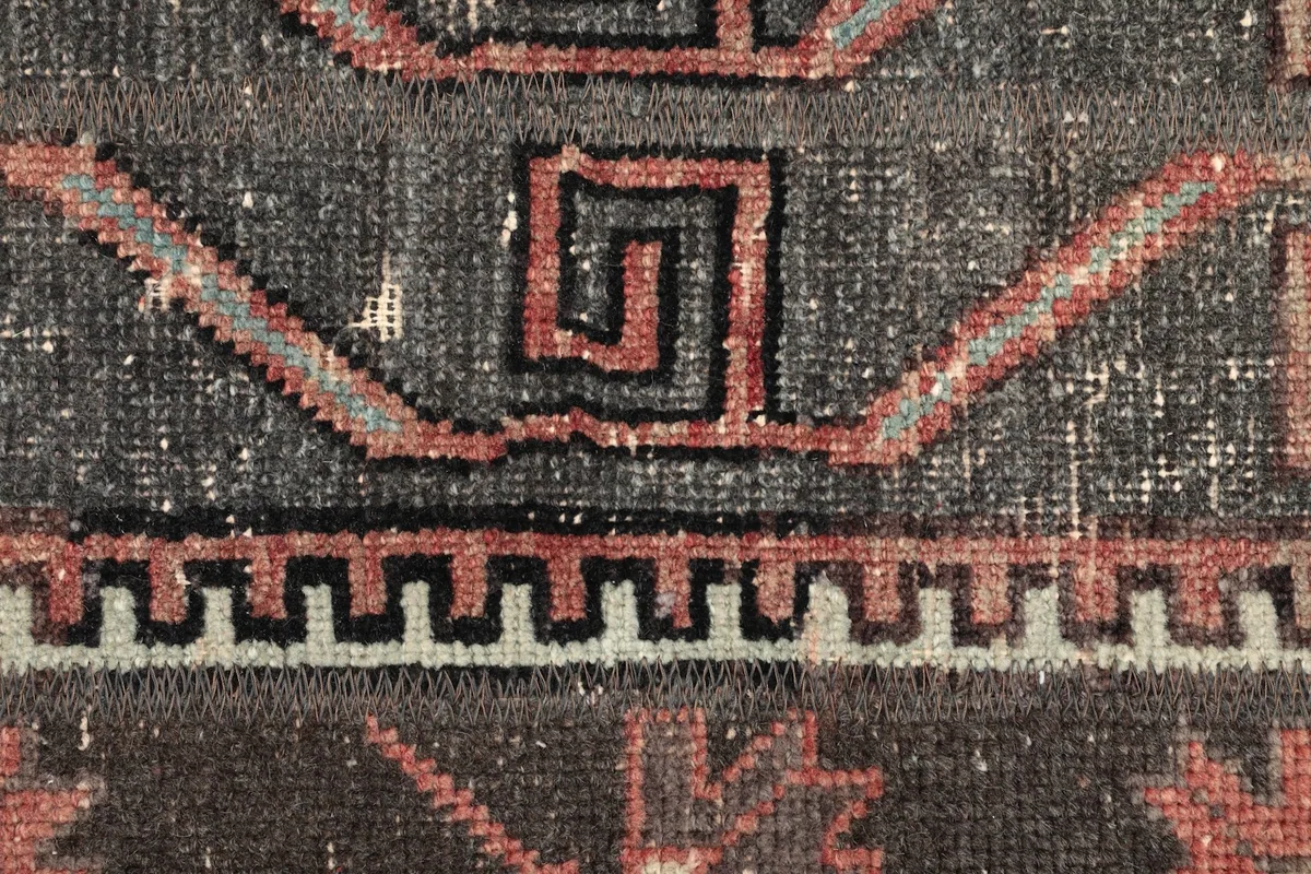 Intricate detail of a rust and black spiral geometric motif within the charcoal field