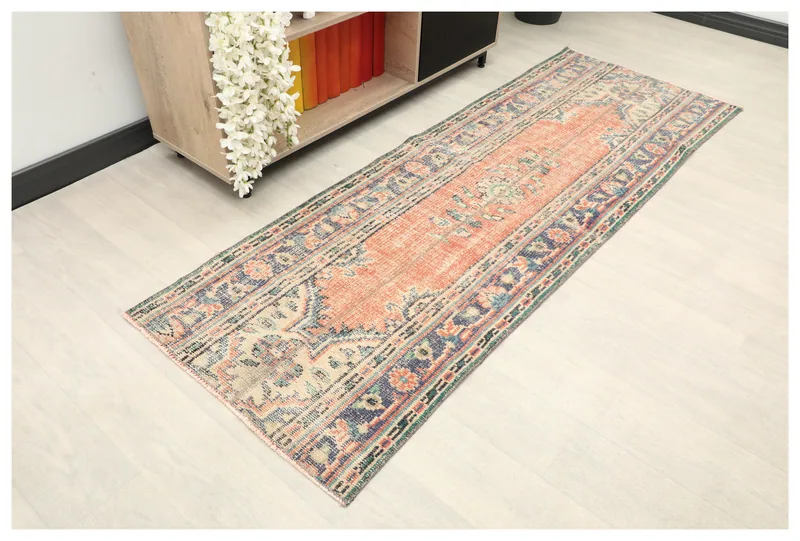 Full top view of the vintage rust and navy Anatolian runner on a white floor.