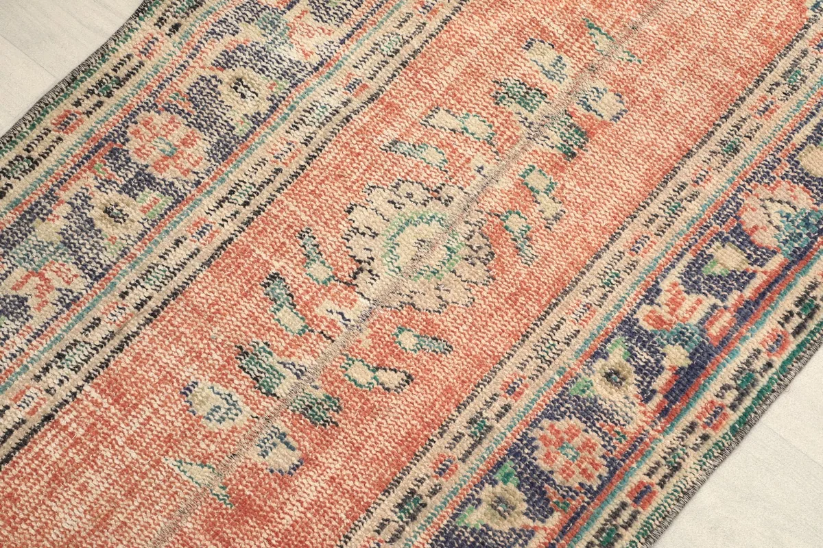 Detailed view of the central floral motif and patina on the rust field of the runner.