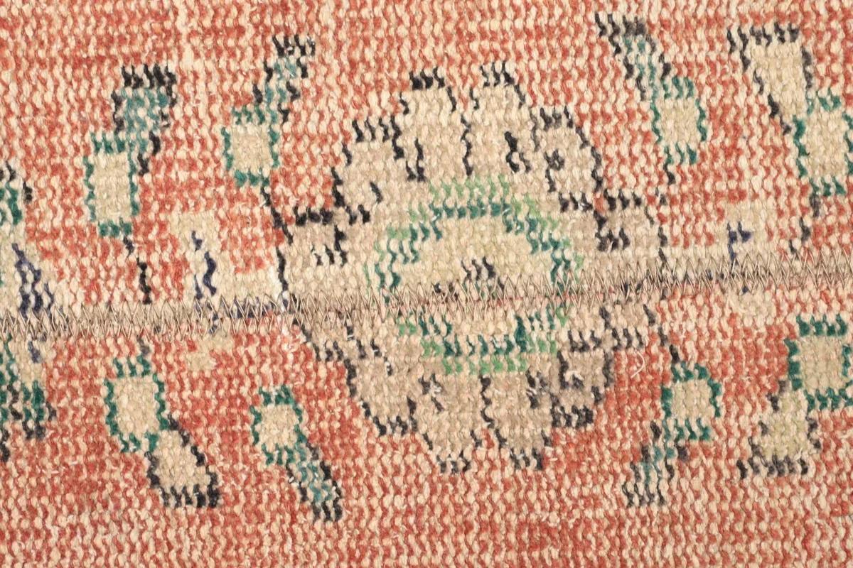 Extreme close-up of the low wool pile, revealing individual knots and faded colors.
