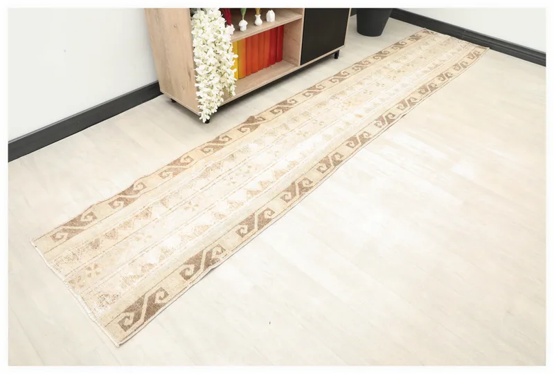 Full top view of the 2'1" x 11'6" beige and brown vintage Anatolian runner rug on a white floor.