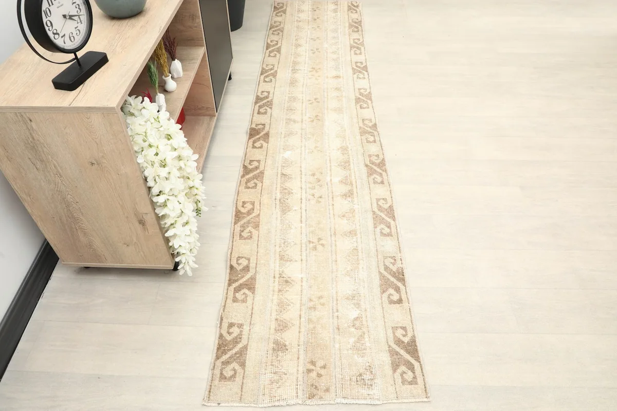 The long runner rug placed in a hallway setting next to a wooden console, showcasing its full length.