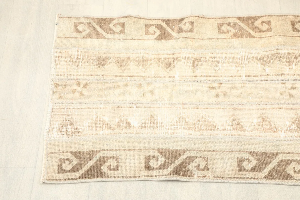 Overhead view of one end of the runner, showing the distinct brown S-motif border and central beige patterns.