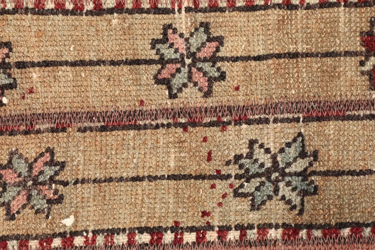 Detailed view of the small floral-like motifs and thin stripes on the tan field