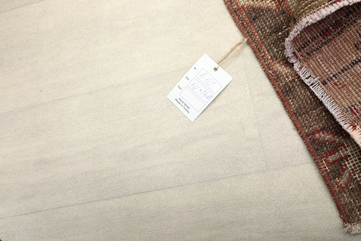 Corner of the rug with a tag, against a light floor, demonstrating its size and authenticity