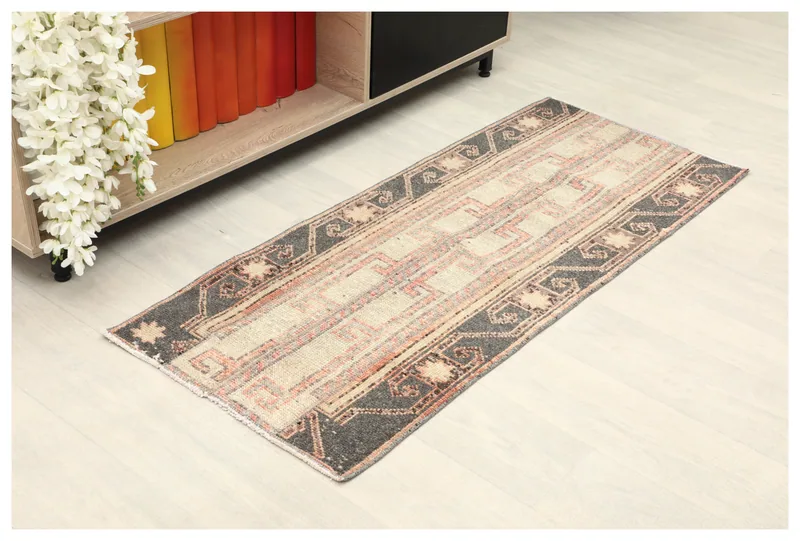 Full top view of the 2x4 beige, rust, and charcoal geometric Anatolian rug on a white floor.