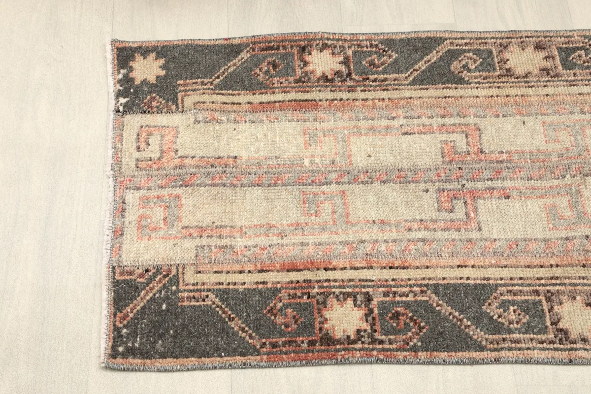 Close-up of the rug's side border with charcoal and beige tribal patterns.