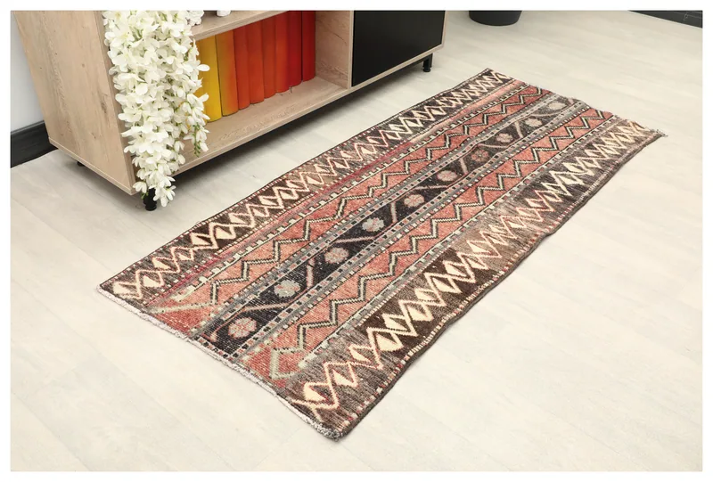 Full top view of the rust, brown, and black geometric vintage Anatolian runner rug on a white background.