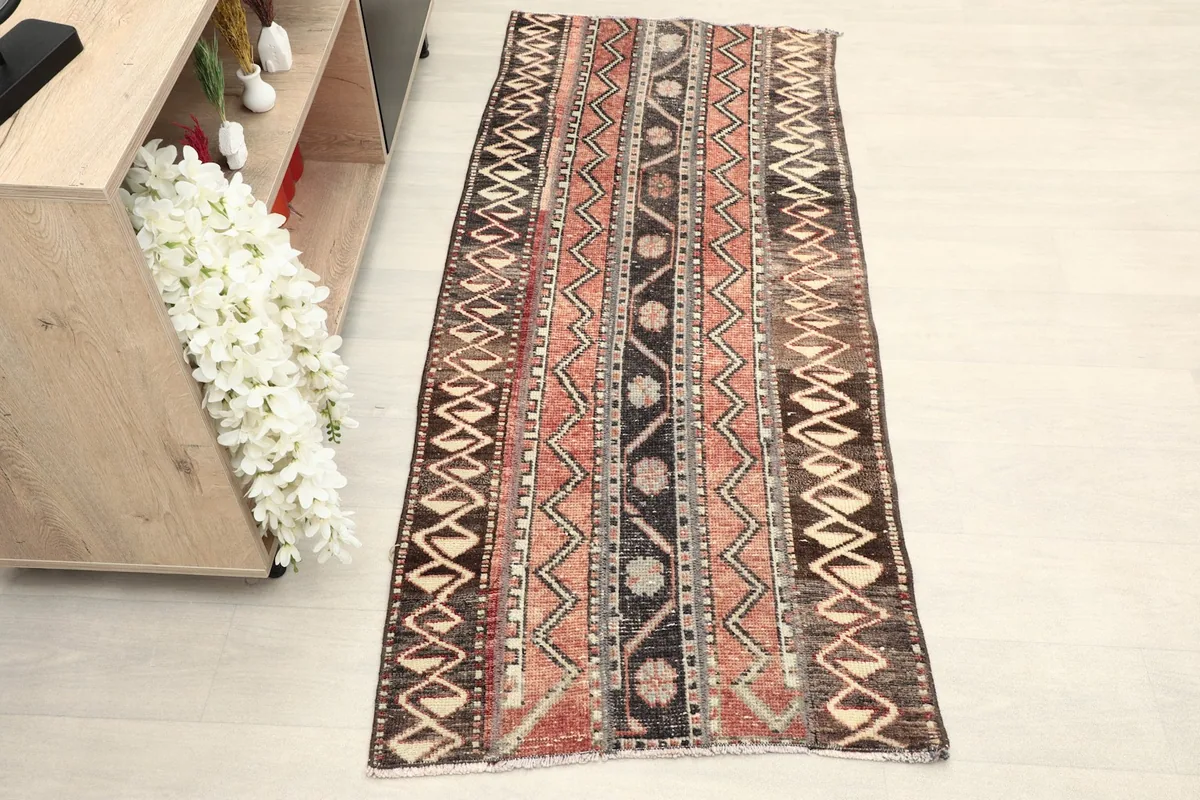 Overhead view of the vintage runner rug placed in a room setting with light flooring and a shelf.