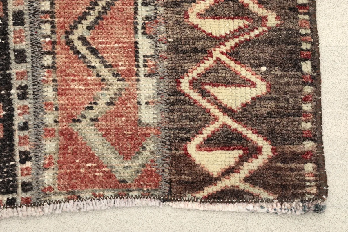 Close-up detail of the rug's end, showing the low pile, geometric patterns, and short fringes.