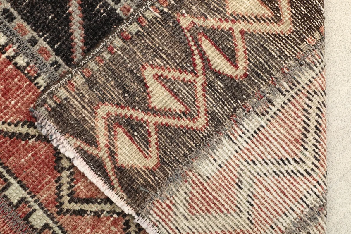 Folded corner of the rug revealing the cotton foundation and the reverse side of the hand-knotted construction.